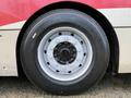 A close-up of a tire on a 2016 Grande West Vicinity bus showcasing a silver rim with multiple black bolts and a black tire with white text