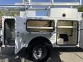 A 2015 Ford F-550 utility truck with an open side compartment revealing shelves and storage space