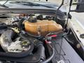 The engine compartment of a 2008 Ford F-450 with a large brown coolant reservoir and various hoses and connectors visible