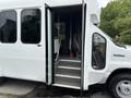 A 2014 Ford E-350 with its door open revealing steps leading inside the vehicle