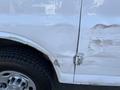 A 2014 Chevrolet Express with a dented passenger side door and scratches on the body near the wheel arch