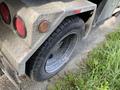 A 2002 Ford F-550's rear tire and part of its metal body with textured diamond plating and red reflectors