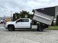 White 2021 Chevrolet Silverado 3500HD pickup truck with a dump bed raised at an angle displaying its cargo area