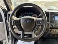 Close-up of the steering wheel of a 2022 Ford F-550 featuring buttons for audio control and cruise settings with the Ford logo in the center