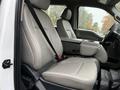 The interior of a 2022 Ford F-550 with gray leather seats and a center console featuring an armrest and storage compartment