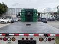 A 2013 Kenworth T370 flatbed truck viewed from the rear with a black textured surface and visible tail lights