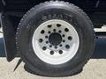 A close-up of a large black tire with white accents featuring multiple circular holes in the rim and the name "SUPERCARGO" printed on the sidewall