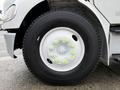A close-up of a black truck tire with a white wheel rim featuring bright green bolts on a 2005 Freightliner M2 106
