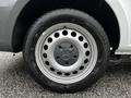 A close-up of the wheel of a 2023 Mercedes-Benz Metris featuring a silver hubcap with circular holes and a black tire with a tread pattern
