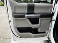 Interior door panel of a 2020 Ford F-350 featuring a handle a speaker grille and a storage compartment in a gray and black color scheme