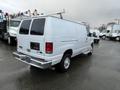 A white 2014 Ford Econoline van with a sliding side door and dual rear doors parked with no visible markings or logos