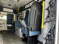 Interior view of a 2013 Chevrolet Express showing a driver's seat and passenger seats with safety harnesses and storage compartments