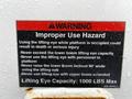 A warning sign attached to a 2013 International DuraStar listing safety hazards related to the lifting eye and boom operations with usage instructions and weight capacity details