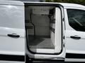 A 2019 Ford Transit Connect van with its side door open revealing a spacious interior with stainless steel flooring and metal storage racks on the walls