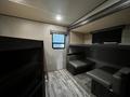 Interior view of a 2021 Grand Design Recreational 311BHS featuring seating area with two benches and a shelf against the wall
