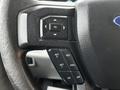 Close-up of the steering wheel controls of a 2016 Ford F-150 featuring buttons for navigation and cruise control settings