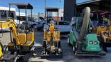 A yellow 2021 Cael-1T Mini excavator with a compact design and controls visible on the operator's seat positioned centrally among other machinery