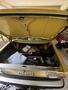 A yellow 1978 Volvo 244 with its trunk open revealing tools and miscellaneous items inside