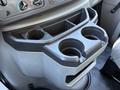 A center console in a 2021 Ford Econoline featuring two cup holders and a storage compartment