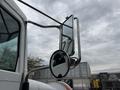A 2016 Peterbilt 348 featuring a chrome side mirror and mirror arm reflecting a cloudy sky
