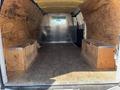 Interior view of a 2012 Chevrolet Express cargo van showing a spacious empty area with wooden benches on either side and a metal panel at the back