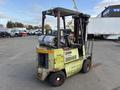 A green and yellow 2000 Clark GPS 15 forklift with a metal propane tank and two wooden forks in the front