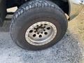 A close-up of a tire mounted on a wheel of a 2007 Ford F-350 SD showing a chrome rim with several holes and a rugged tread pattern