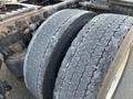 A close-up of two worn tires on a 2022 Freightliner Cascadia showing visible tread wear and a rough surface on the rubber