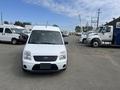 A white 2010 Ford Transit Connect is parked facing the camera with a blank front license plate and a compact design typical of utility vans