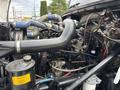 A view of the engine compartment of a 1998 Freightliner FL80 showcasing pipes wiring and mechanical components