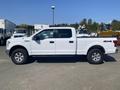 A white 2017 Ford F-150 truck with a crew cab and four-wheel drive parked on a lot, featuring chrome rims and a bed cover