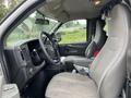 Interior view of a 2014 GMC Savana showing the driver's seat steering wheel and dashboard with various controls and a cluttered appearance