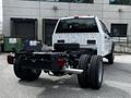 A 2024 Ford F-550 chassis cab with a white body and dual rear wheels is parked with its bed exposed showcasing the vehicle's frame and wheels