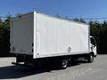A white 2020 Hino 155 box truck with a clean and smooth cargo area and a simple rear design parked at an angle showing its rear and left side