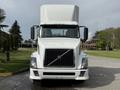 A white 2012 Volvo VNL truck with a distinctive grille and large front cab is parked facing forward showing its headlights and side mirrors