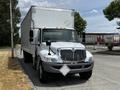 A 2019 International 4300 box truck with a white cargo area and a chrome grille parked on the side of a road