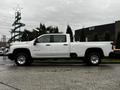 A white 2021 Chevrolet Silverado 3500HD pickup truck parked with a crew cab and bed for hauling in a side view angle