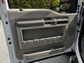 Interior door panel of a 2009 Ford F-550 featuring a handle a large storage compartment and various controls for windows and locks