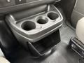 A cup holder unit with three circular indentations for cups and a small open storage compartment below in the interior of a 2014 GMC Savana
