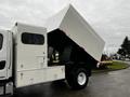 A side view of a 2007 Freightliner M2 106 truck with an elevated dump bed allowing for loading and unloading materials