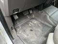 The interior floor of a 2010 Ford F-150 showing the driver side pedals and a rubber floor mat with dirt marks