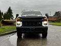 A 2021 Chevrolet Silverado 3500HD with a bold front design featuring a black grille and prominent headlights parked on a wet road