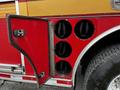 A red fire truck with an open compartment door revealing six cylindrical storage spaces for equipment or tools