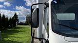 A 2016 Isuzu NPR truck with a side mirror in focus showing the driver's side and a portion of the windshield