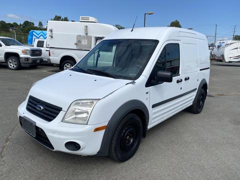 A white 2013 Ford Transit Connect van parked with a black front grille and wheels showing a compact design suitable for cargo transport