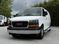 A white 2023 GMC Savana van is parked with a black grille and chrome bumper featuring the GMC logo on the front