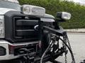 Close-up of a 2011 Ford F-550 front grille with mounted headlights and a tow hitch assembly featuring chains and hydraulic lines
