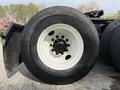 Close-up of a large black tire with a white rim mounted on a 2012 Volvo VNL, displaying intricate tread patterns and lug nut design