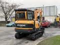 A 2022 Hyundai R55-9A mini excavator with a yellow and black exterior is displayed in the foreground with tracks and a protective cage over the operator's area