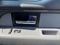 Interior door handle of a 2014 Ford F-150 with a chrome finish and surrounding gray panels featuring window control buttons